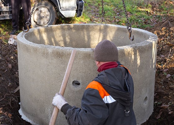 A worker installs a sewer into the ground — Precast Concrete Products in Yamba, NSW